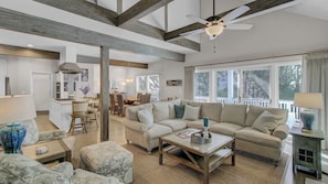 A spacious living room with a large sofa, a coffee table, and a dining area with chairs.