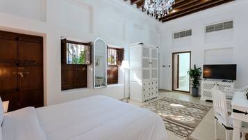 A bedroom with a large bed, a wardrobe, a TV, and a chandelier.
