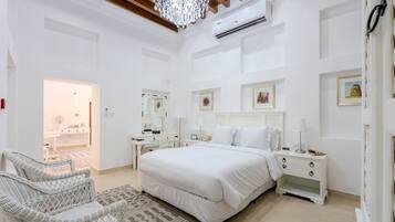 A bedroom with a large bed, a nightstand, a dresser, a chair, and a chandelier.