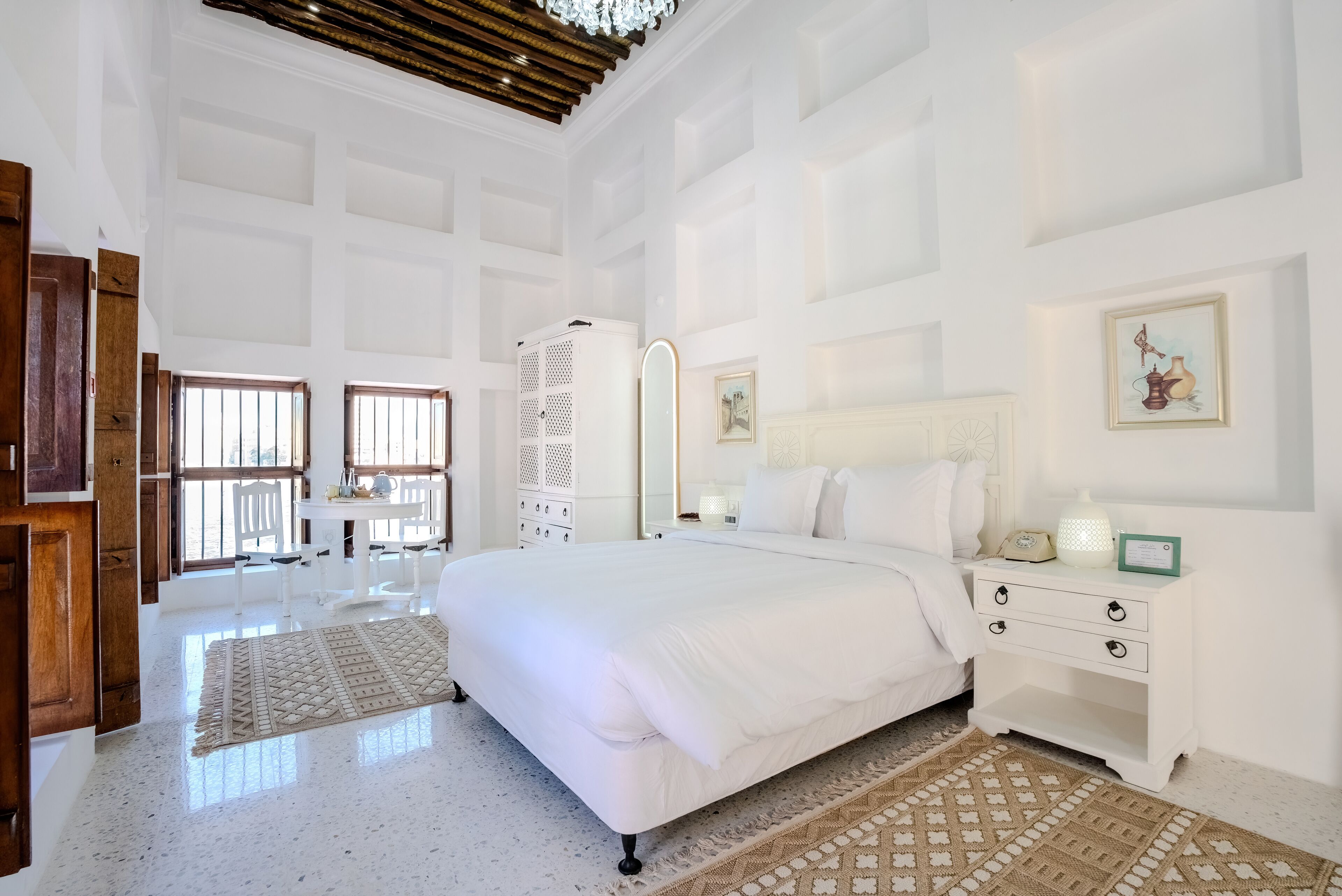 Une chambre spacieuse avec un grand lit, une table de chevet, une commode et une fenêtre donnant sur un beau paysage.