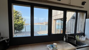 A kitchen with a large window overlooking a waterfront. - Beautiful wooden house with sea view (Gujan-Mestras)