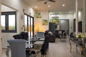 Ein modernes Wohnzimmer mit Essbereich, großen Fenstern und Kunstwerken an den Wänden.