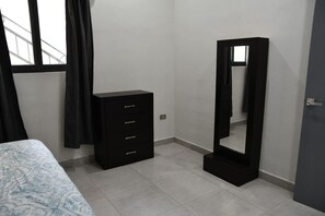 Ein Schlafzimmer mit einem Bett, einer schwarzen Kommode und einem großen Spiegel.