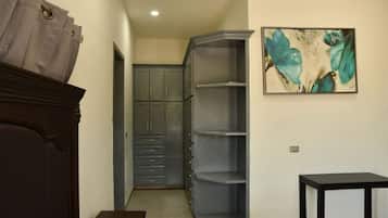 A room with a wardrobe, a painting, and a small table.