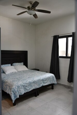 A bedroom with a bed, a ceiling fan, a window with curtains, and a nightstand. - Casa de Cuatro Vientos (Ãlamos)