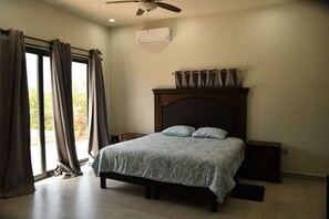 A bedroom with a bed, curtains, a ceiling fan, and a window with curtains.