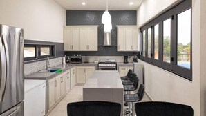 Una cocina moderna con una isla central, armarios blancos, un refrigerador de acero inoxidable y un ventanal con vistas al exterior.