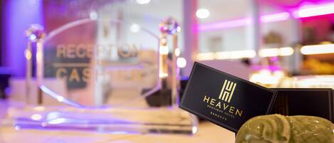 Una mesa de recepción con un cartel que dice "RECEPTION CASHIER" y una tarjeta negra con la inscripción "HEAVEN BOUTIQUE HOTEL BANGKOK".