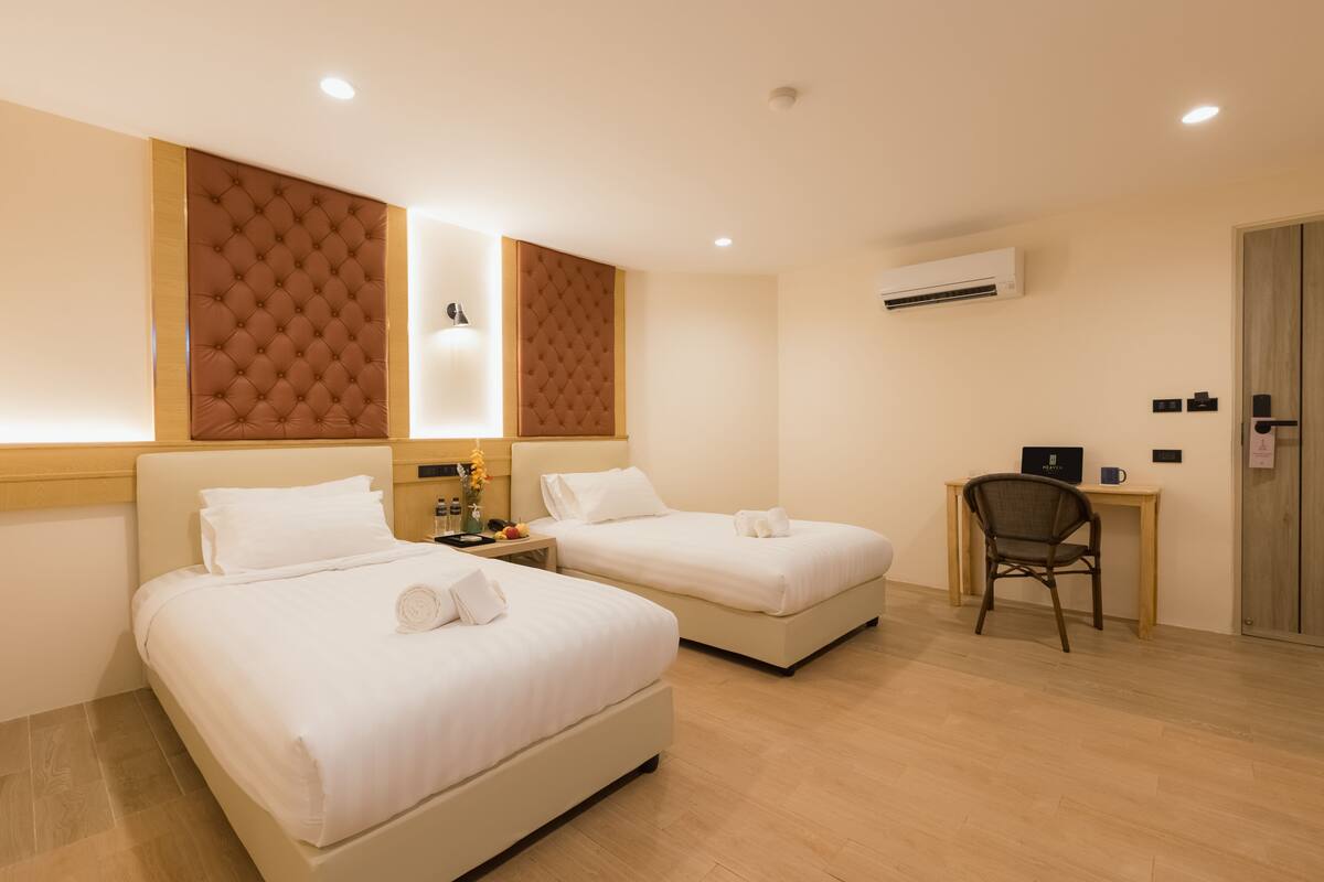 Une chambre d’hôtel avec deux lits, un bureau et un appareil de climatisation.
