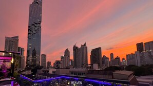 Un paisaje urbano al atardecer con un rascacielos destacado y un edificio con la inscripción 