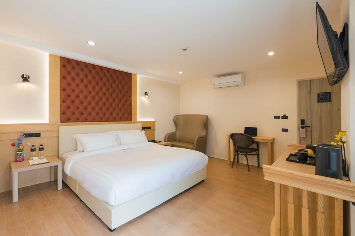 Une chambre d’hôtel avec un grand lit, un bureau, une chaise et un téléviseur.