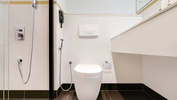 Un baño moderno con inodoro, ducha y secamanos.