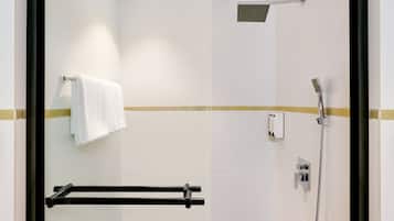 A modern bathroom with a glass shower enclosure, a towel rack, and a handheld showerhead.
