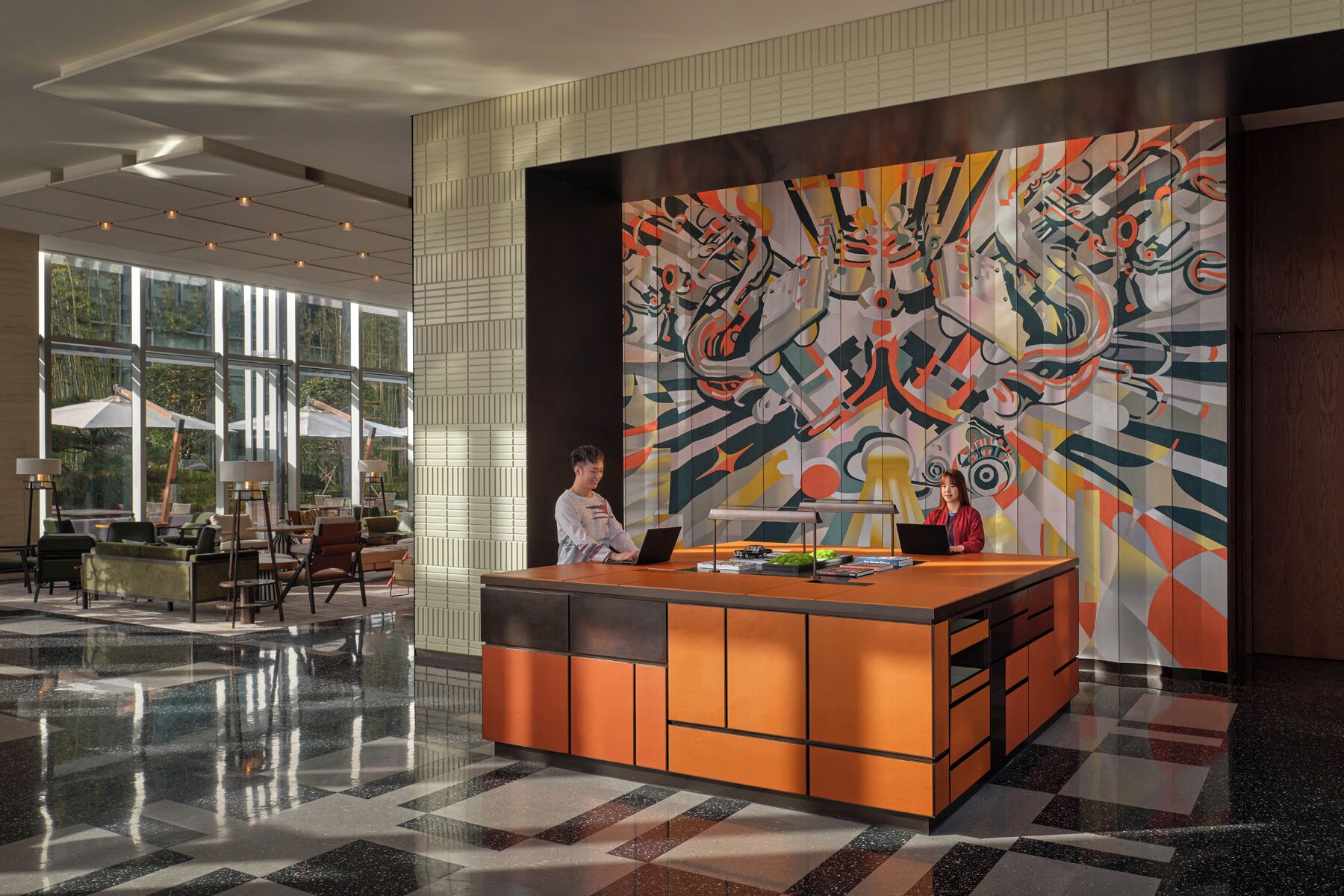 A modern lobby with a reception desk, large windows, and a colorful abstract mural.