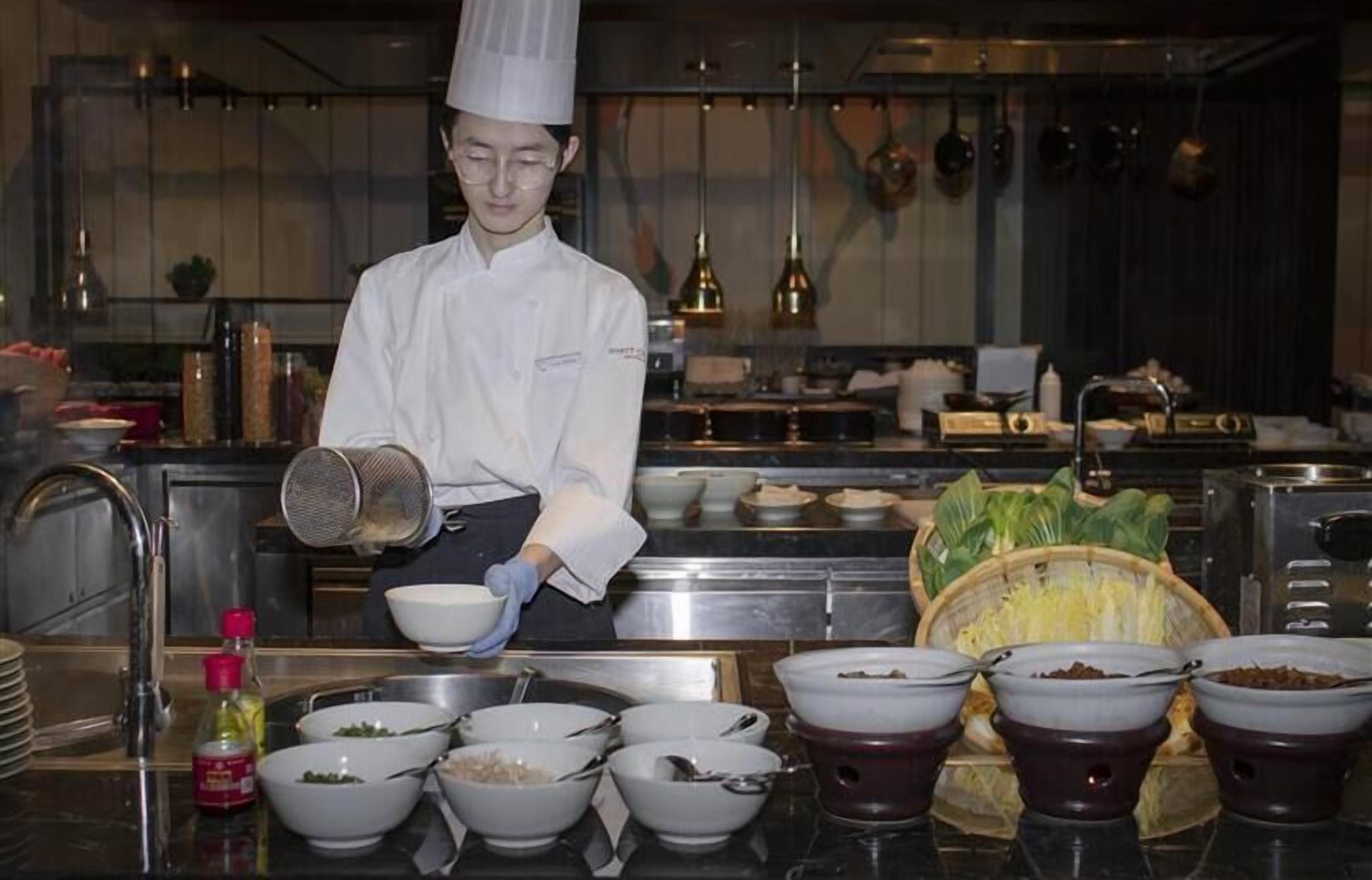 Un chef en una cocina profesional, con diversos utensilios de cocina e ingredientes.