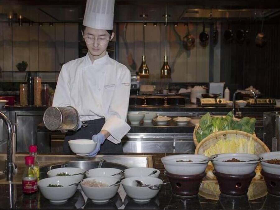 Un chef en una cocina profesional, con diversos utensilios de cocina e ingredientes.