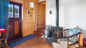 A cozy cabin interior with a wooden interior, a fireplace, a dining area, and a door leading outside. - Seaside Log Cabin, Carna (Carna)