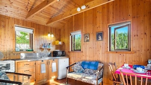 A wooden cabin interior with a kitchen, dining area, and a sofa. - Seaside Log Cabin, Carna (Carna)