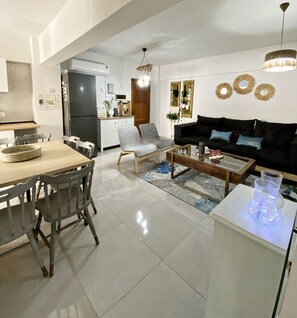 Eine moderne Küche mit Kühlschrank, Esstisch und Stühlen. Ein Wohnbereich mit Sofa und Couchtisch.