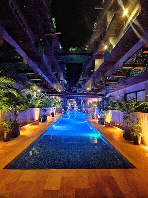 An indoor pool with a central water feature, surrounded by potted plants and benches. - Estudio Asteroide- prime location! (Tulum)
