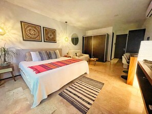 A modern bedroom with a large bed, a bedside table, a nightstand, a chair, a desk, and a wardrobe. - Estudio Asteroide- prime location! (Tulum)