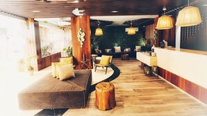 Una moderna zona de recepción con suelo de madera, un mostrador de recepción y un área de estar con sofá y sillones.