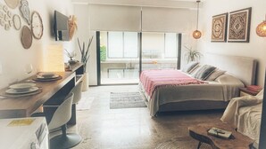 Un dormitorio moderno con cama, escritorio y ventanas amplias.