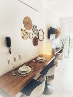 A modern dining area with a wooden table, chairs, and wall-mounted plates. - Estudio Asteroide- prime location! (Tulum)