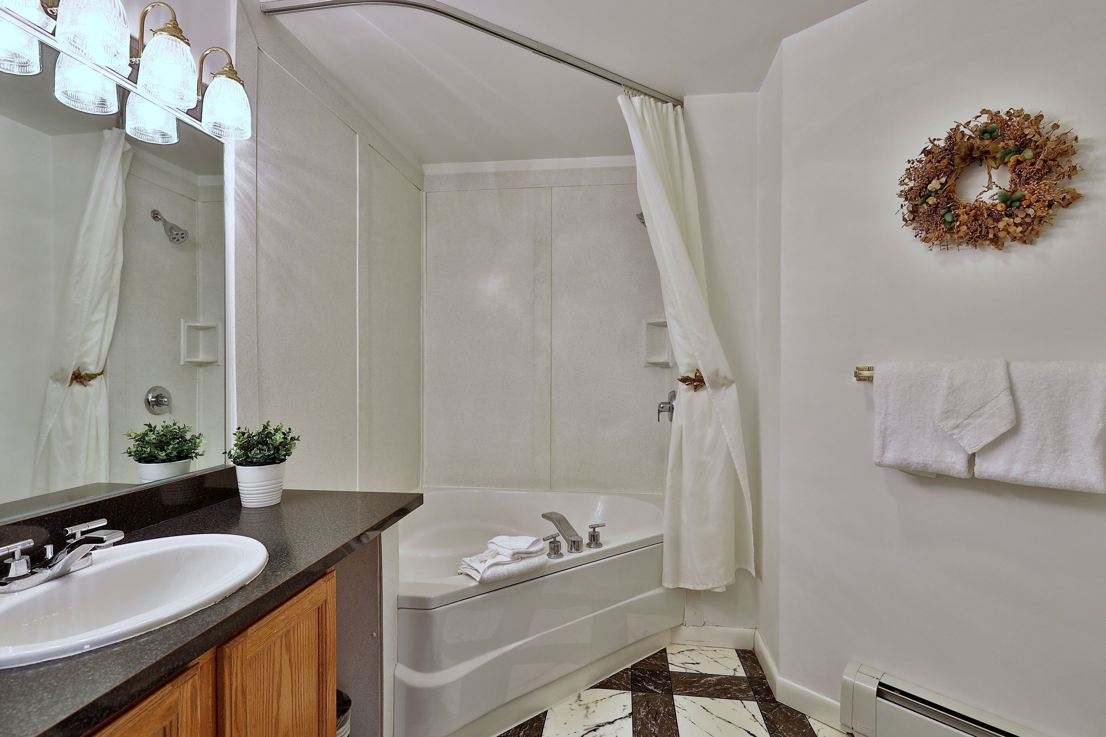 A bathroom with a sink, mirror, shower, and bathtub.