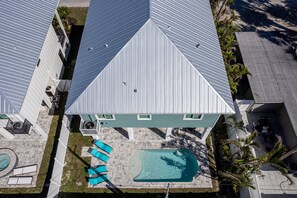 Luftaufnahme eines Gebäudes mit Schwimmbecken, mehreren Balkonen und einer Dachterrasse.
