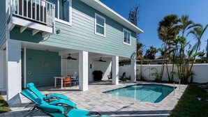 A poolside area with lounge chairs, a covered patio, and a swimming pool. - 233 Delmar Avenue - Beautiful Private Pool Home 3 Bedroom Home by RedAwning (Fort Myers Beach)