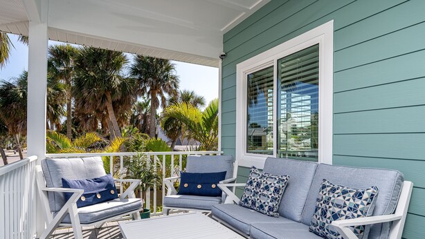 A covered outdoor seating area with a white table and two sofas with blue cushions. - 233 Delmar Avenue - Beautiful Private Pool Home 3 Bedroom Home by RedAwning (Fort Myers Beach)