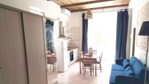 En kompakt bolig med tekøkken, spiseplads og opholdsområde med sofa.