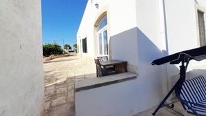 En hvid bygning med en terrasse, et bord og en stol.