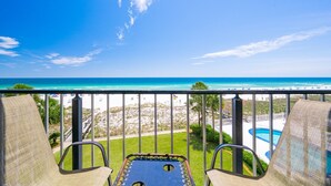 A balcony with two chairs and a pool table, overlooking a beach and ocean. - Breakers 43 2 Bedroom Condo (Orange Beach)