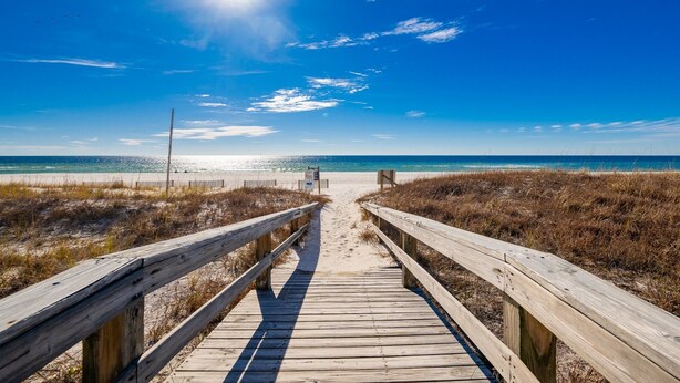 A wooden boardwalk leading to a beach with a clear sky and the sun shining. - Breakers 43 2 Bedroom Condo (Orange Beach)