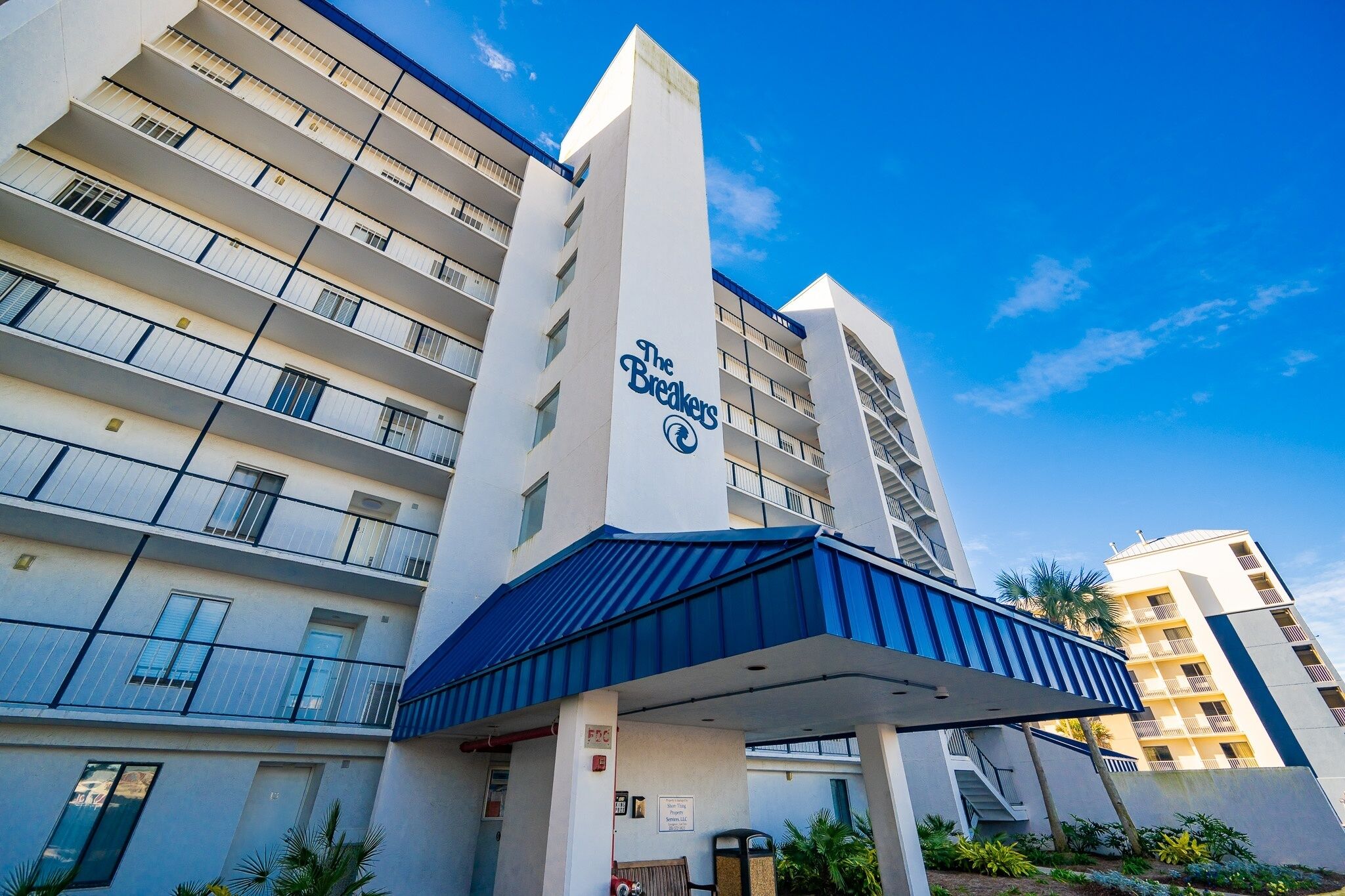 A multi-story hotel with balconies, a prominent entrance, and a clear sky.
