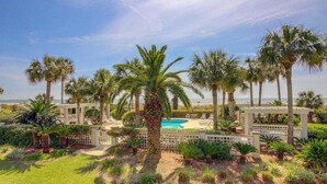 A pool area with palm trees and a white pergola structure.
