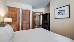 Ein Hotelzimmer mit einem Bett, einem Fernseher, einem gerahmten Foto an der Wand und Holztüren.