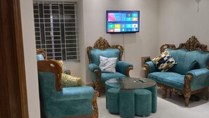 A living room with teal sofas, a wooden coffee table, and a ceiling fan. - Stunning 1-bed Apartment in Dhaka Close to Airport (Dhaka)