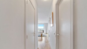 A hallway with white walls and wooden flooring leading to a dining area with a table and chairs. - Sunrise D0 - Bright 3-bedroom apartment with large terrace and frontal sea view (De Haan)
