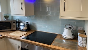 A modern kitchen with a built-in stove, microwave, and kettle. - Modern 2-bed House and Parking Tibshelf Derbyshire (Alfreton)