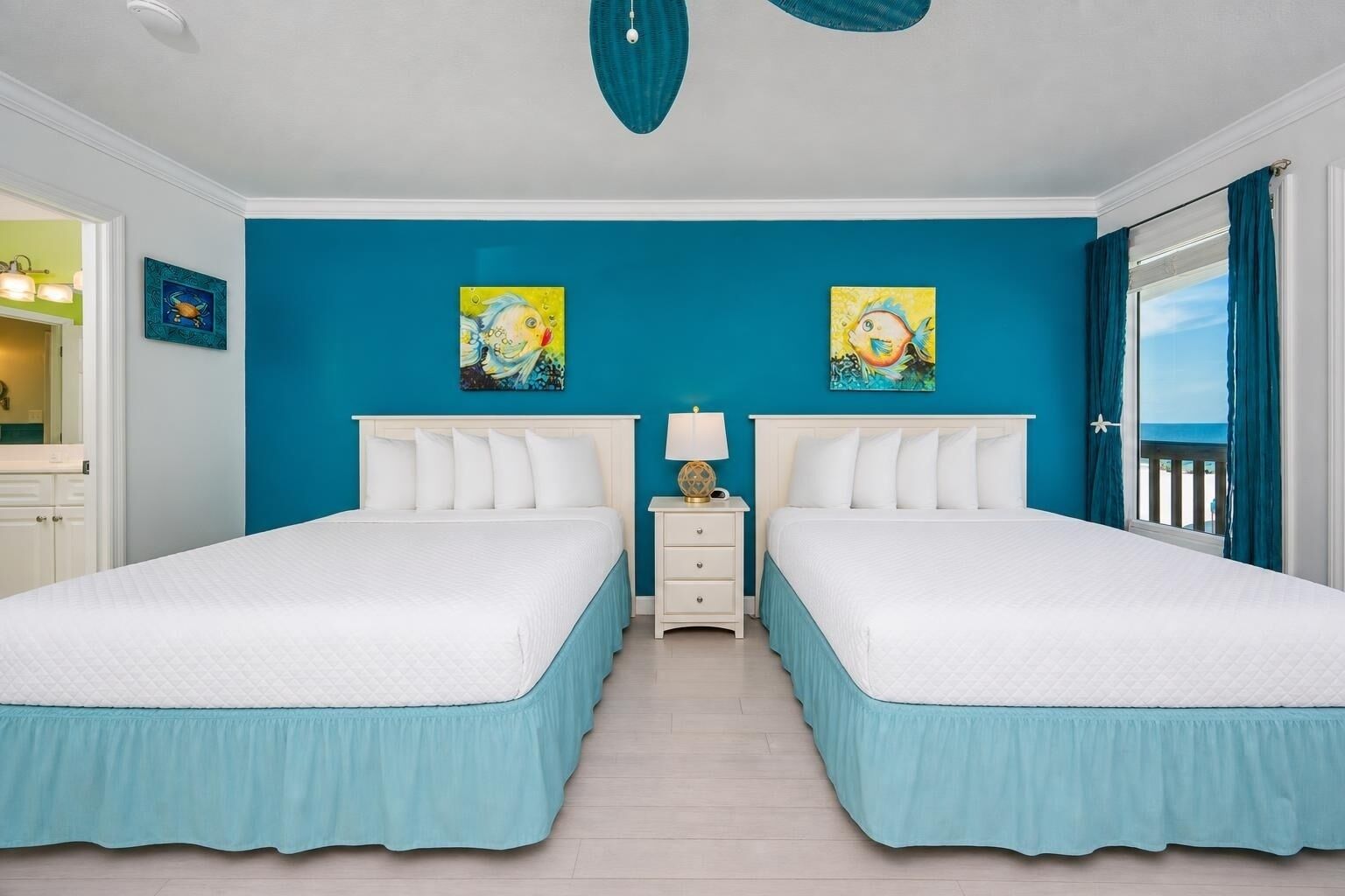 A hotel room with two beds, a nightstand, and artwork on the walls.