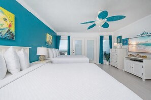 Ein Schlafzimmer mit zwei Betten, einem Deckenventilator, einem Fernseher und Meerblick.