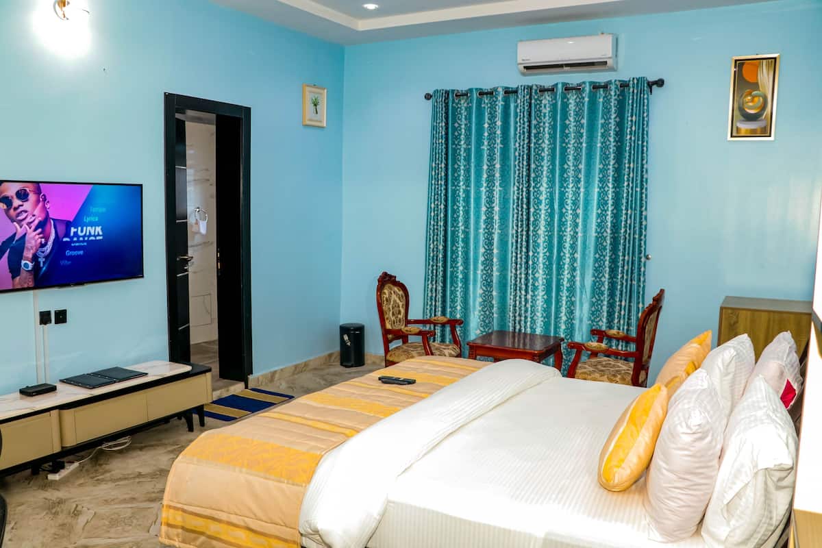 A hotel room with a bed, a TV, a desk, and a chair.