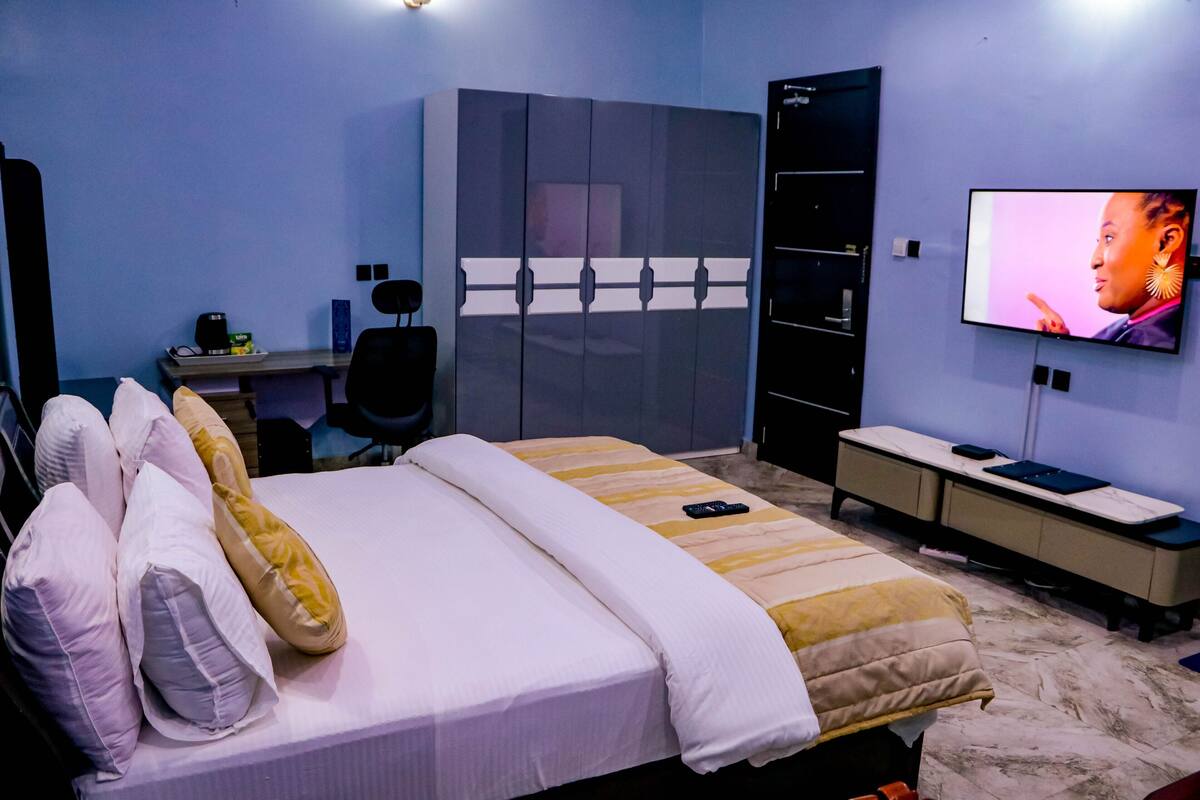A hotel room with a bed, a desk, a TV, and a wardrobe.