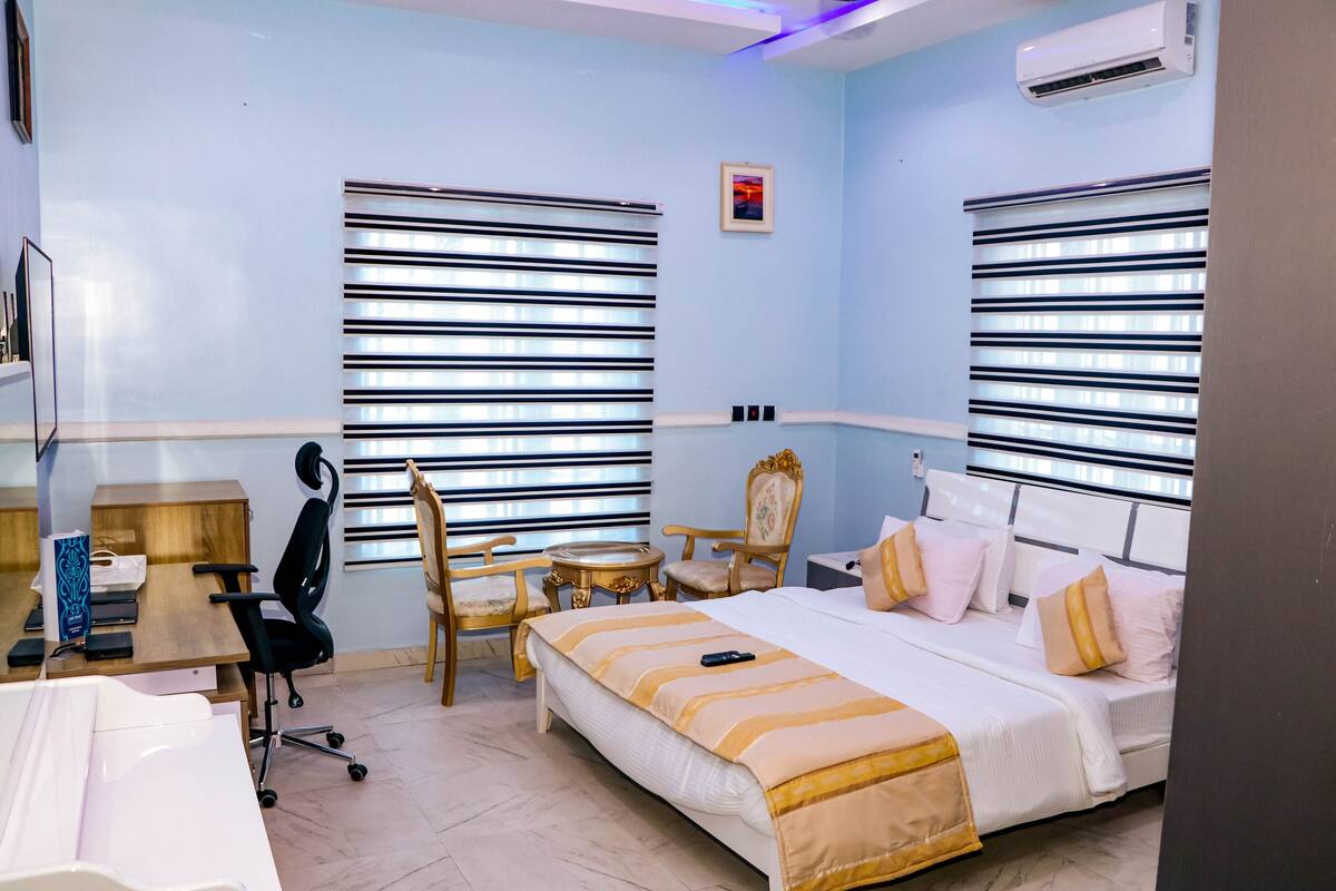 A hotel room with a bed, desk, chairs, and a small table.