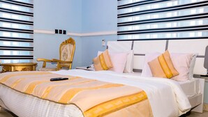 Una habitación de hotel con una cama grande, una mesita de noche, una silla y una ventana con persianas.
