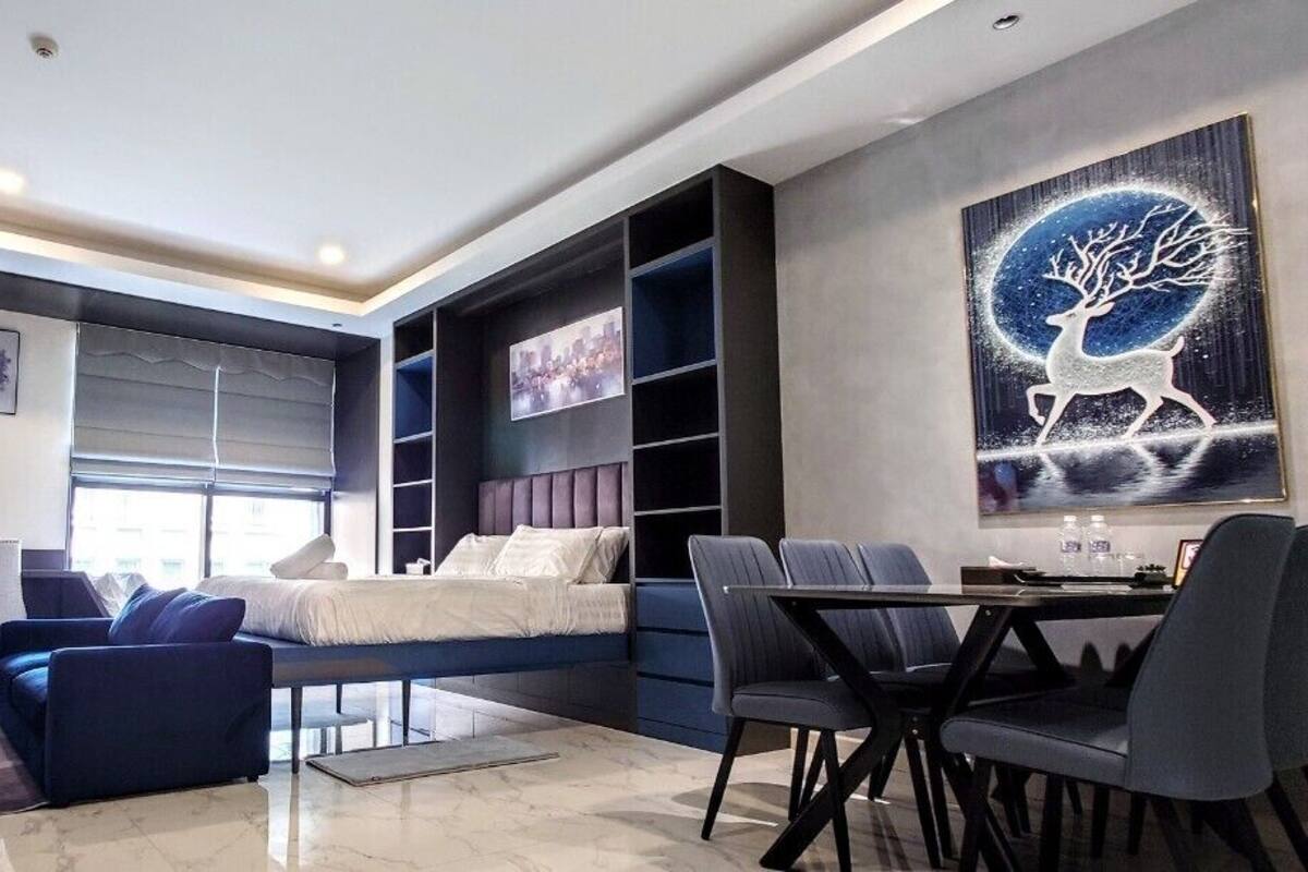 A modern hotel room with a bed, seating area, and a large painting.