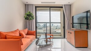 A modern living room with a sofa, a glass table, and a TV. - The Rixx Madison (Ho Chi Minh City)